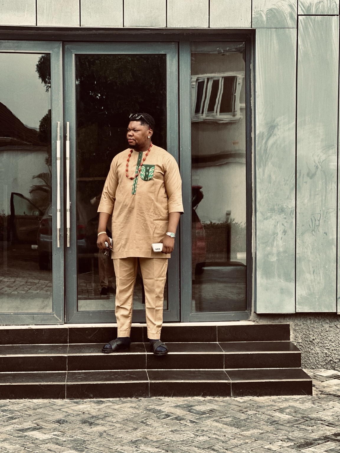 Ciphervenom wearing tan traditional attire outside a building